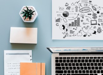 Picture of a desk with a cactus plant, laptop, notebooks, pad and cartoon diagram image