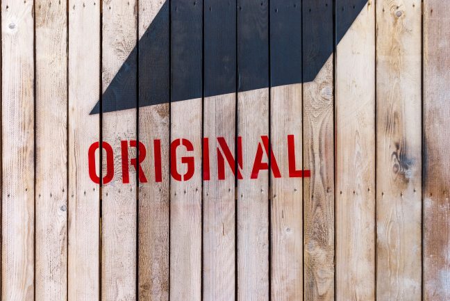 Picture of wood fence with the word 'original' stencilled onto it in red