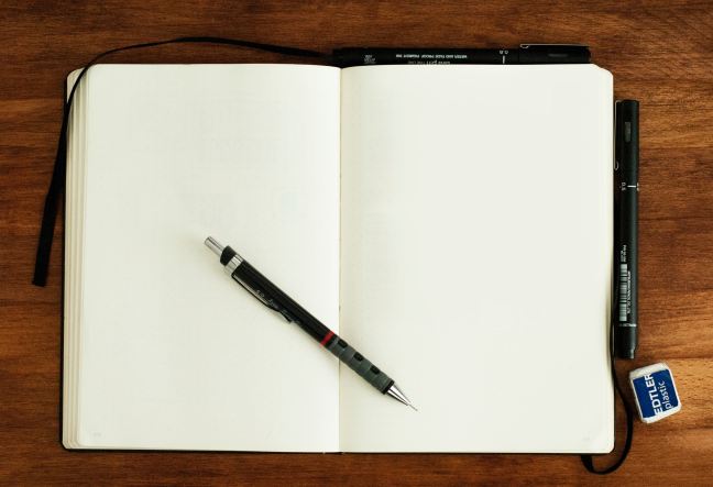An open notebook with blank pages and a pen