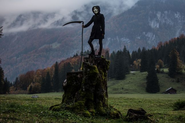 Grim reaper character standing on a rock with a scythe